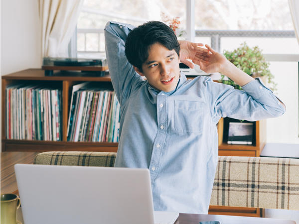 仕事の合間に伸びをする男性ビジネスマンの写真