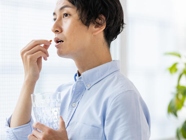 薬を飲む男性の写真