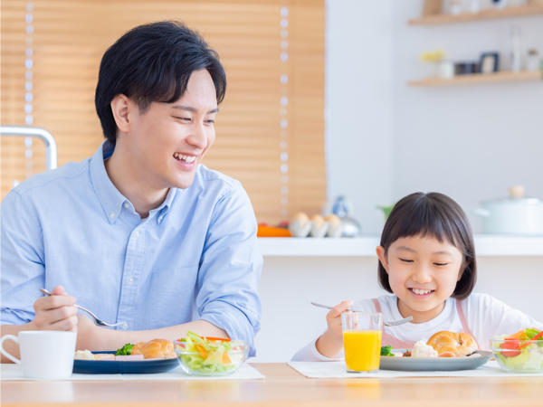 朝食をとる父親と娘の写真