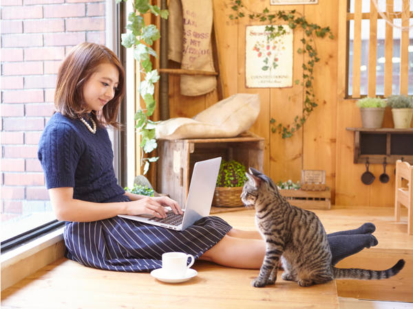 窓辺でパソコンを使う女性の写真