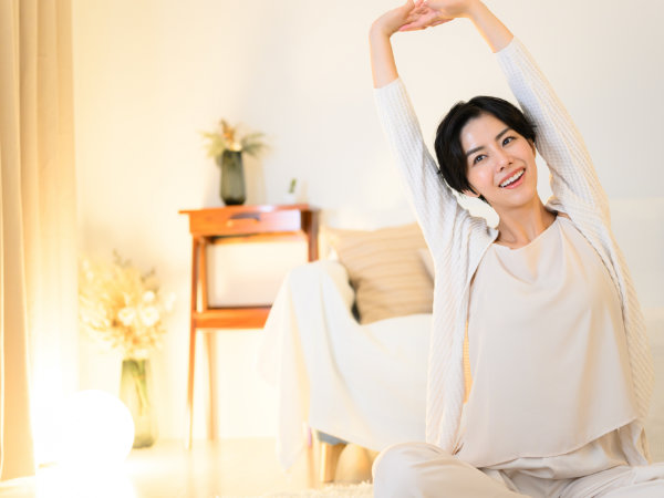 ベッドで伸びをする女性の写真